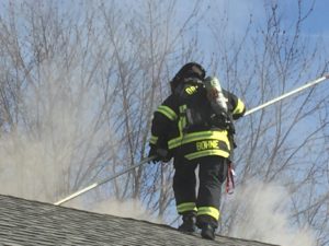 Fireman fighting a fire on the roof of a house